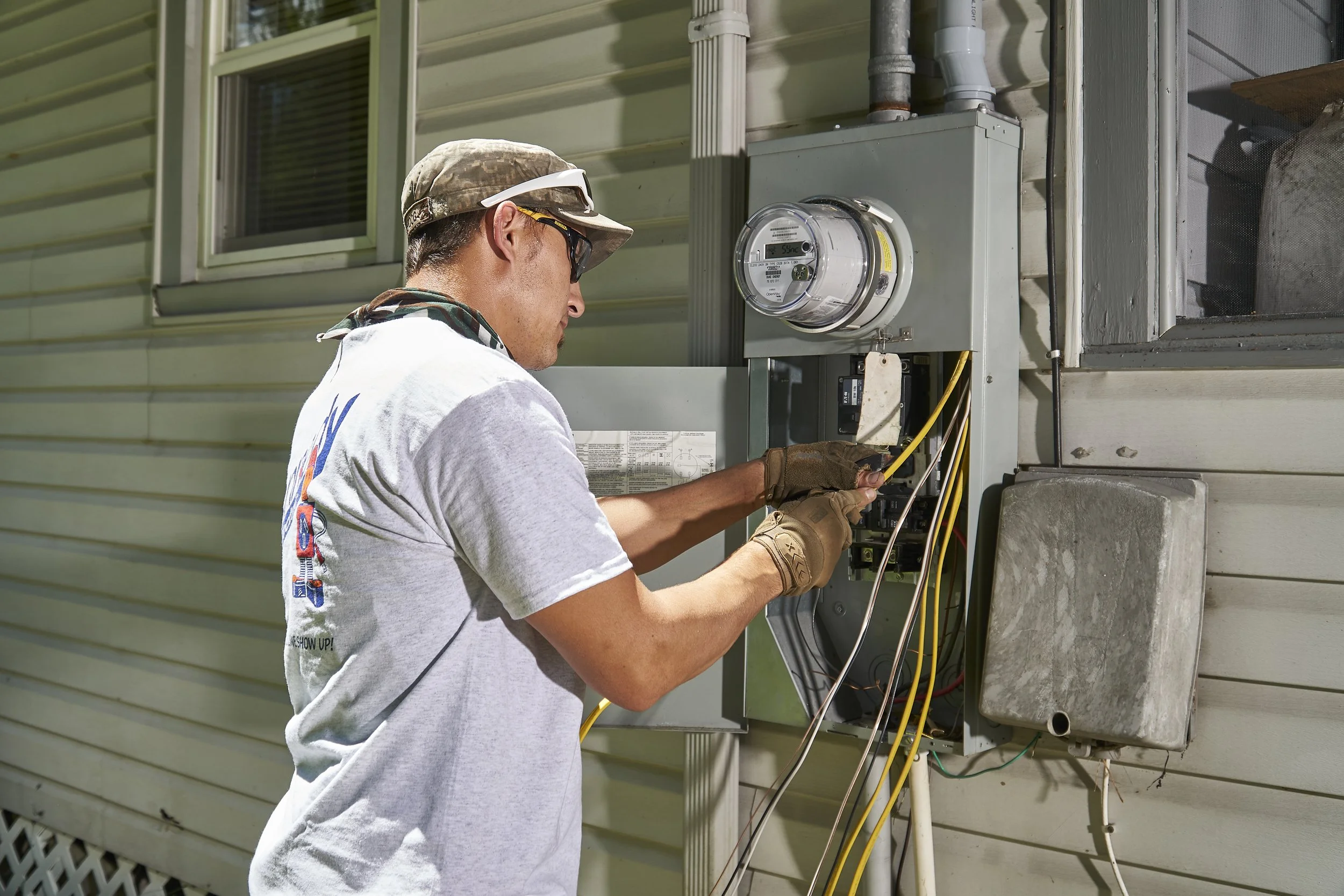 Electrician at an exterior meter/panel on a house
