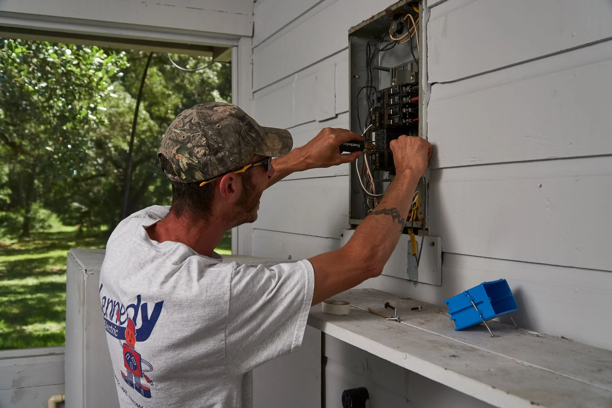 Electrician at an open exterior panel on a porch wall