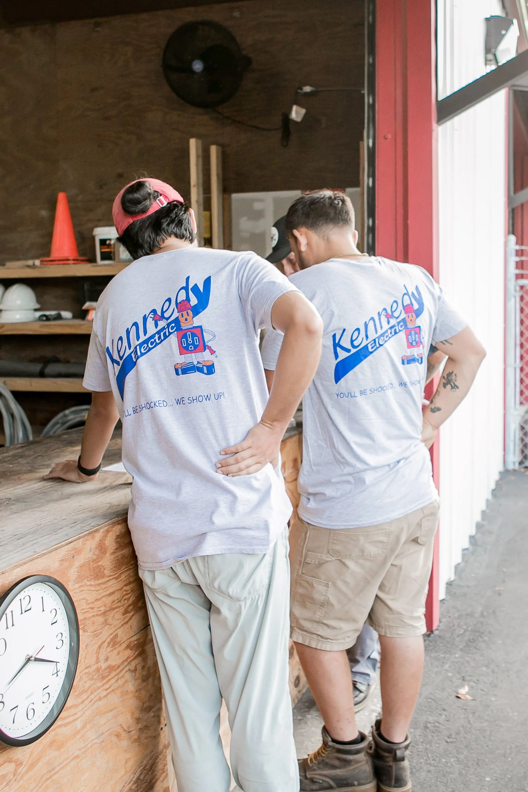 Two workers bent over a shop workbench, backs turned