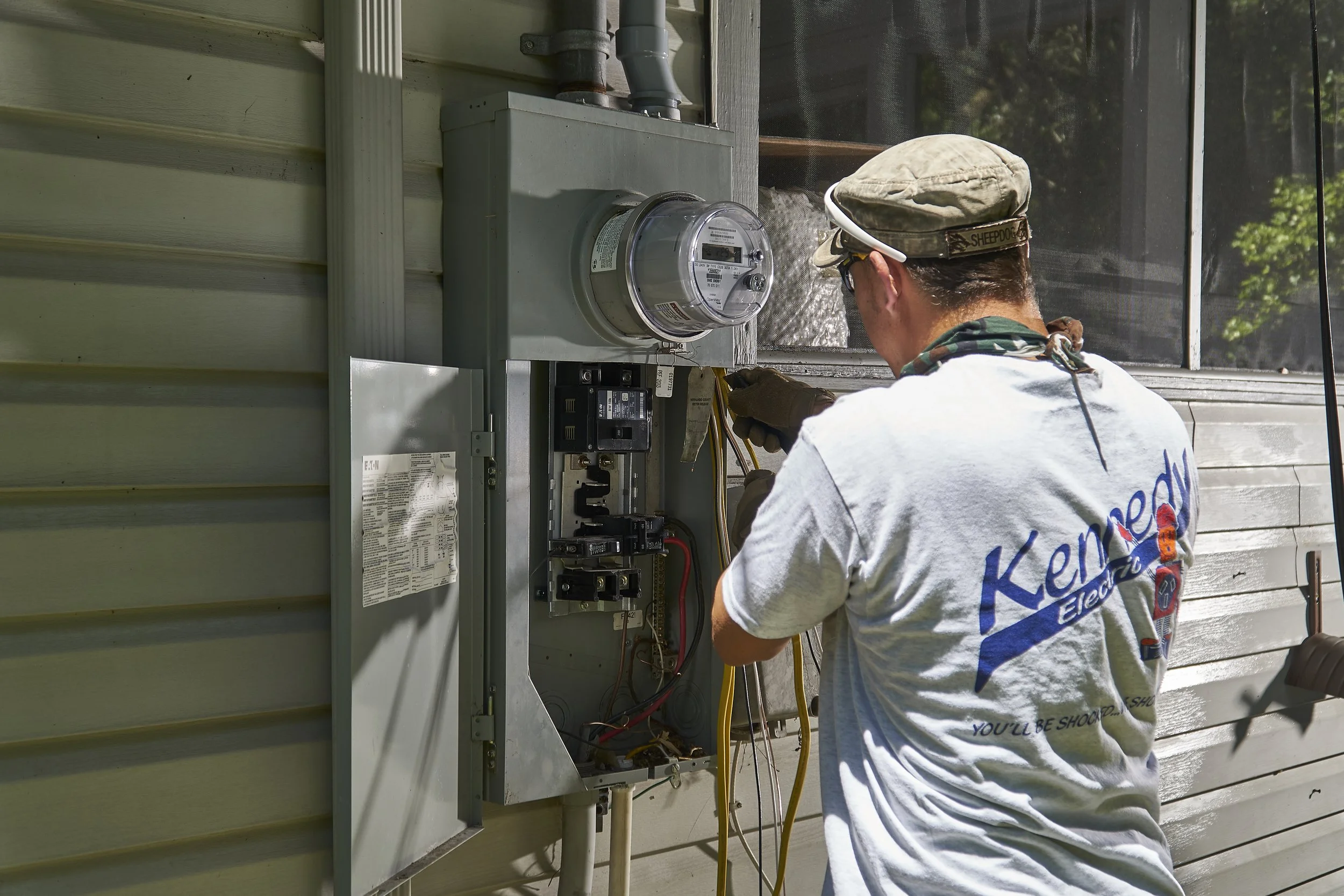 Electrician at an exterior meter/panel on a house (another angle)