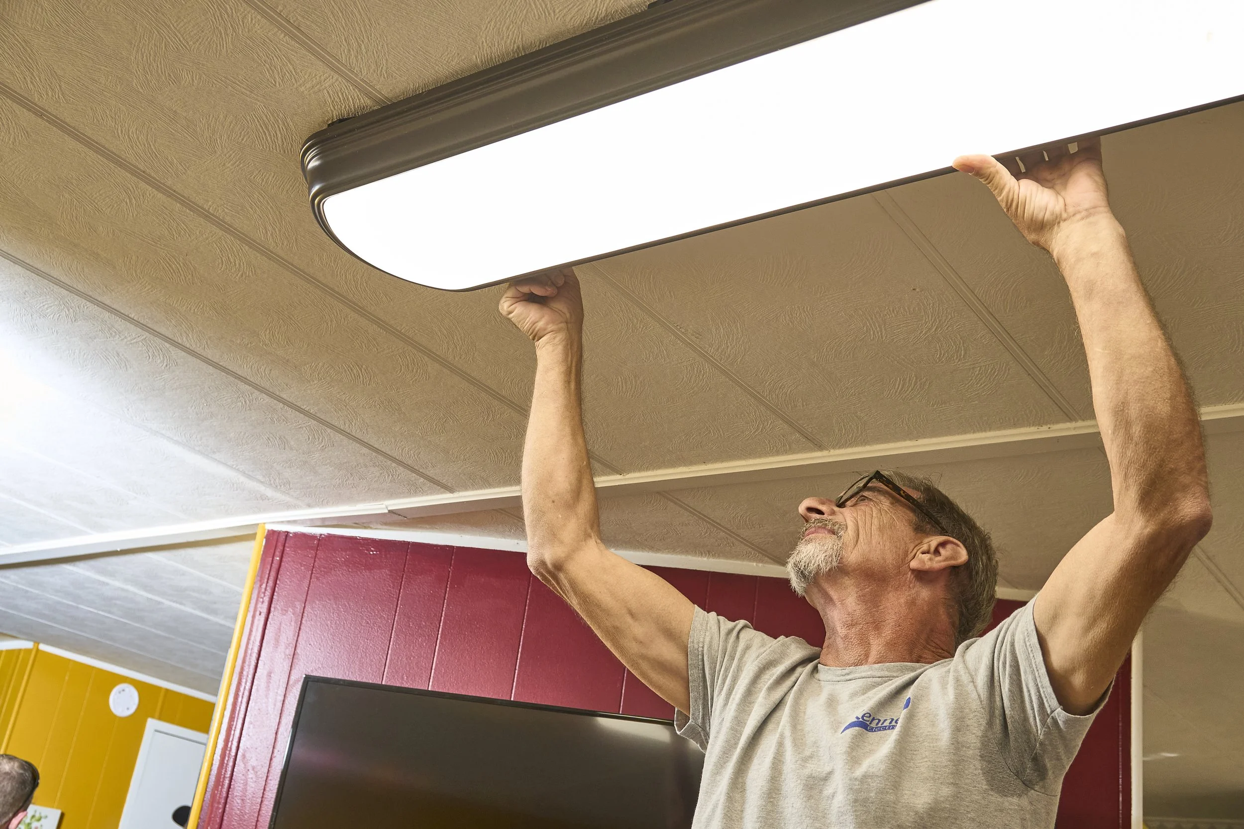 Man installing a linear LED ceiling light fixture