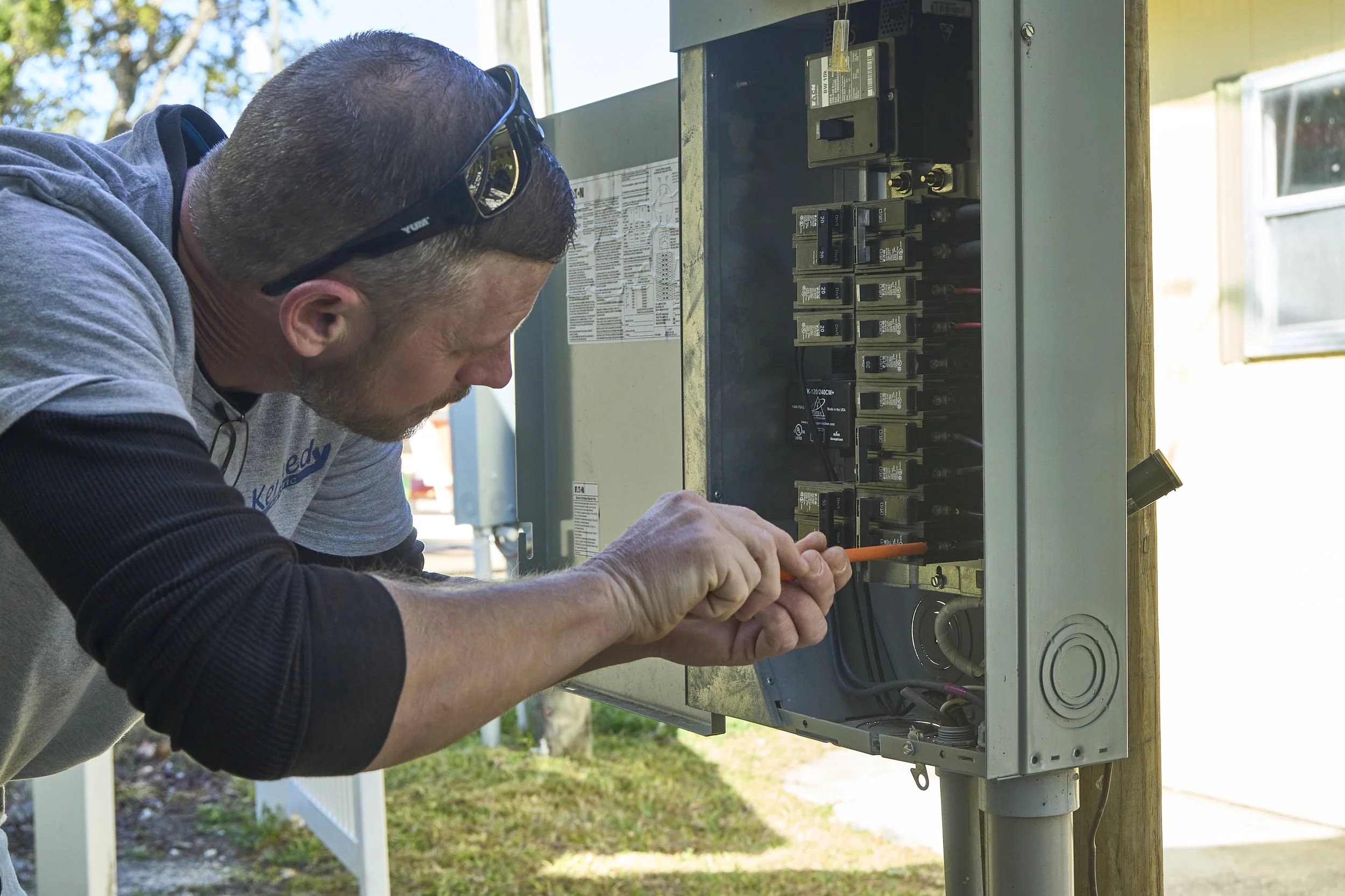 Man at an open exterior breaker panel/meter working