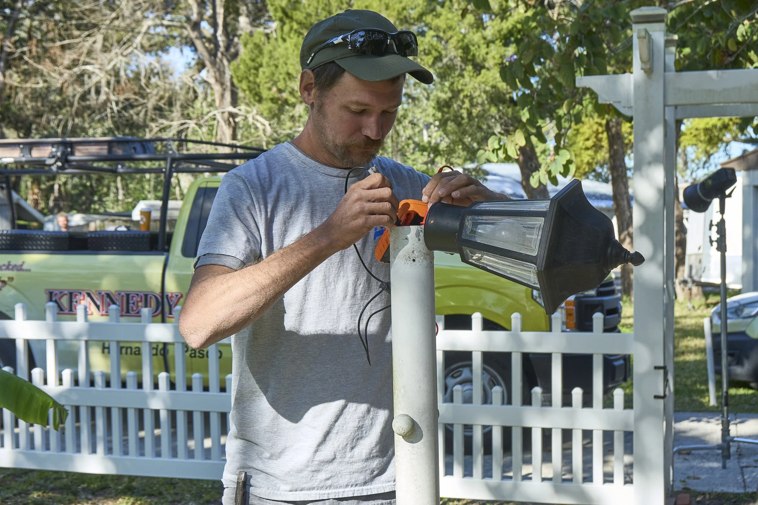 Man installing a lantern post light on a white column