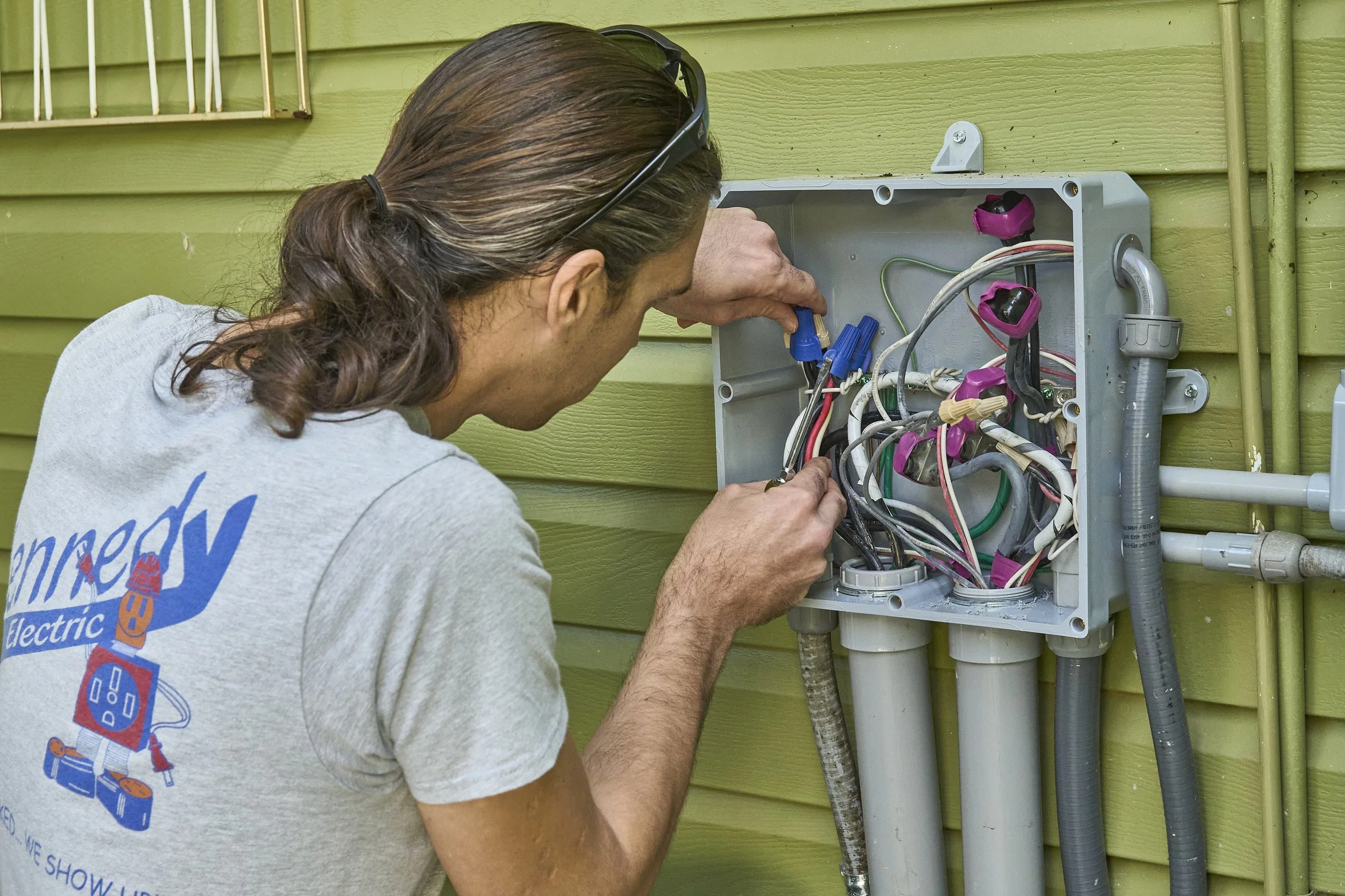Electrician (Kennedy shirt) at an open exterior junction box