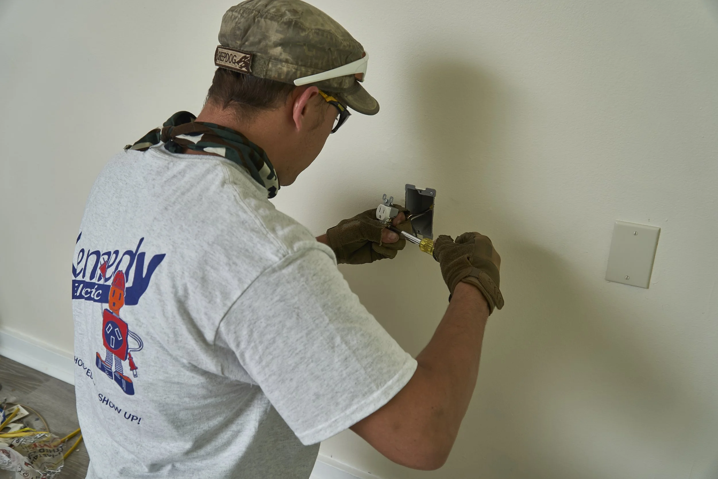 Electrician (back) working on an interior wall box/outlet