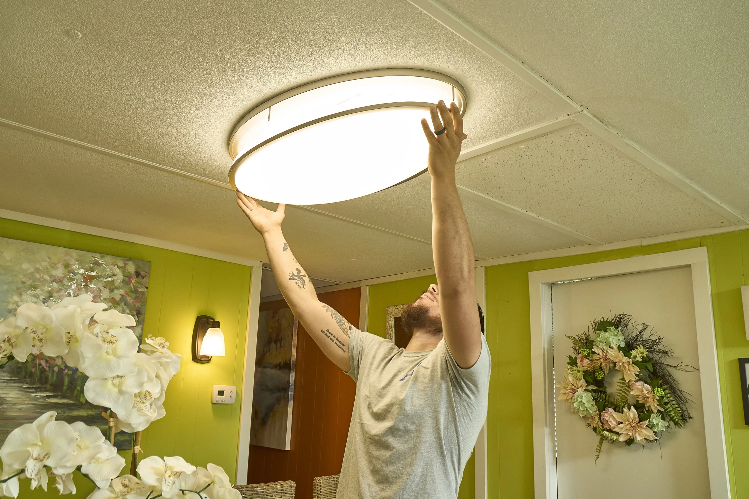 Man installing a round flush ceiling light indoors