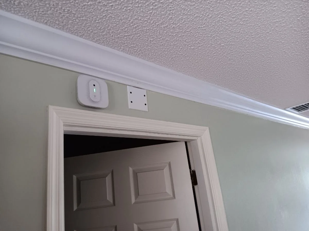 Hardwired interconnected smoke alarm in the hall outside a garage door in a Spring Hill, FL home.