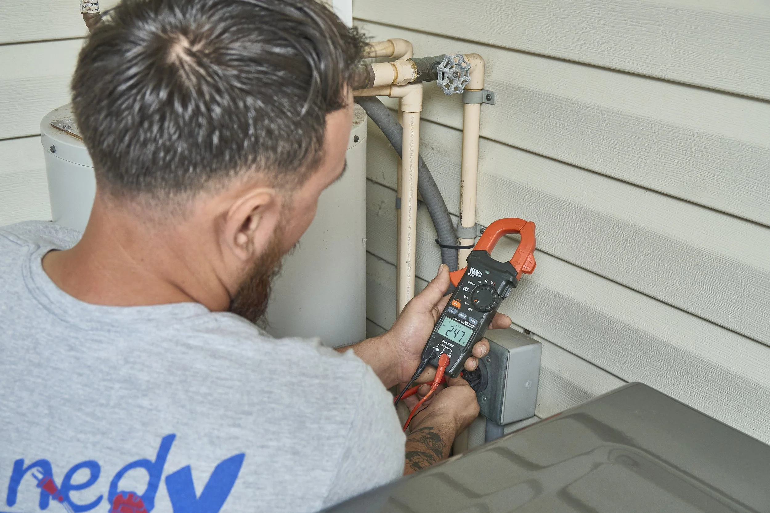 Electrician using a clamp meter on wiring at an exterior post near water