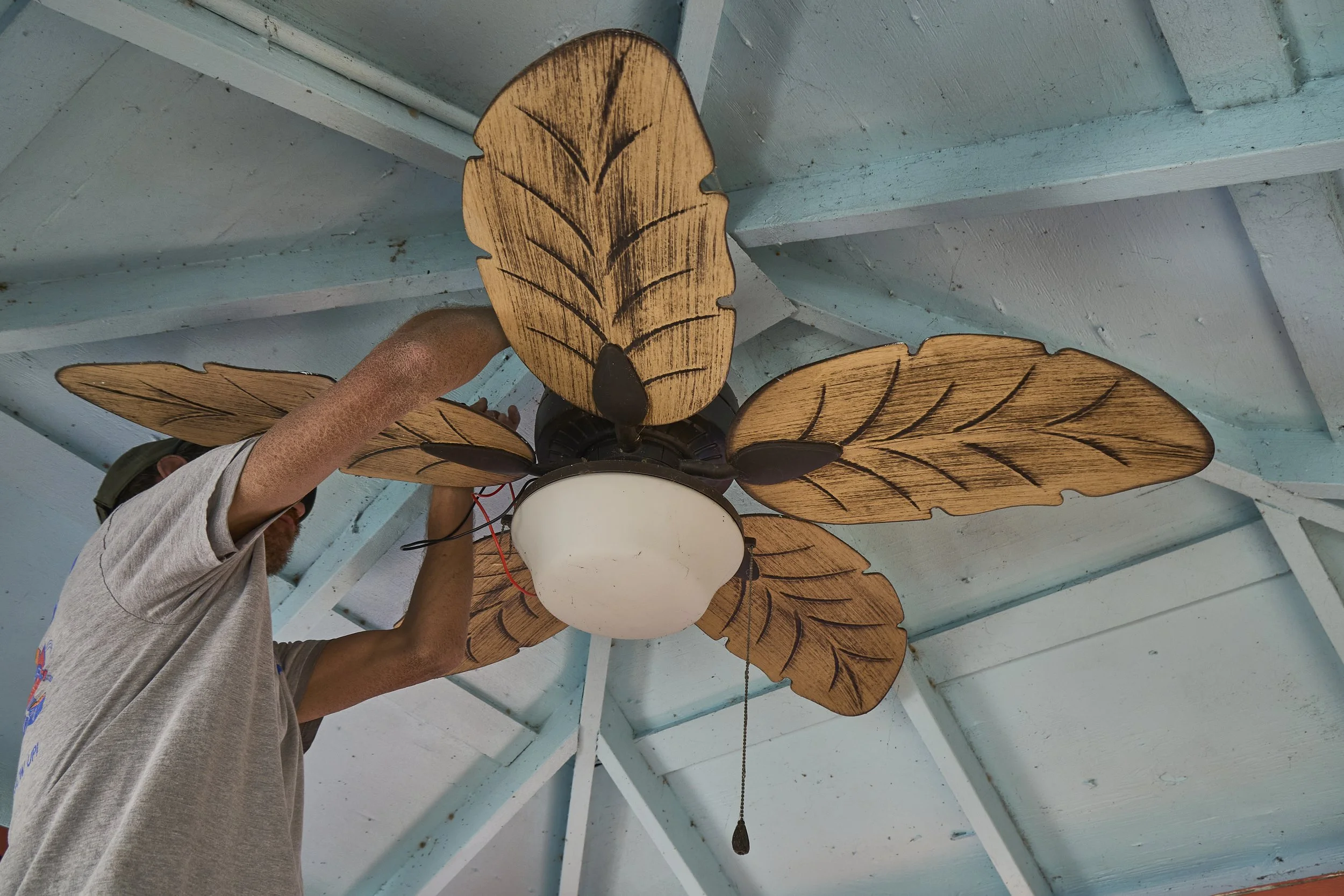 Installed palm-leaf ceiling fan under a wood porch ceiling