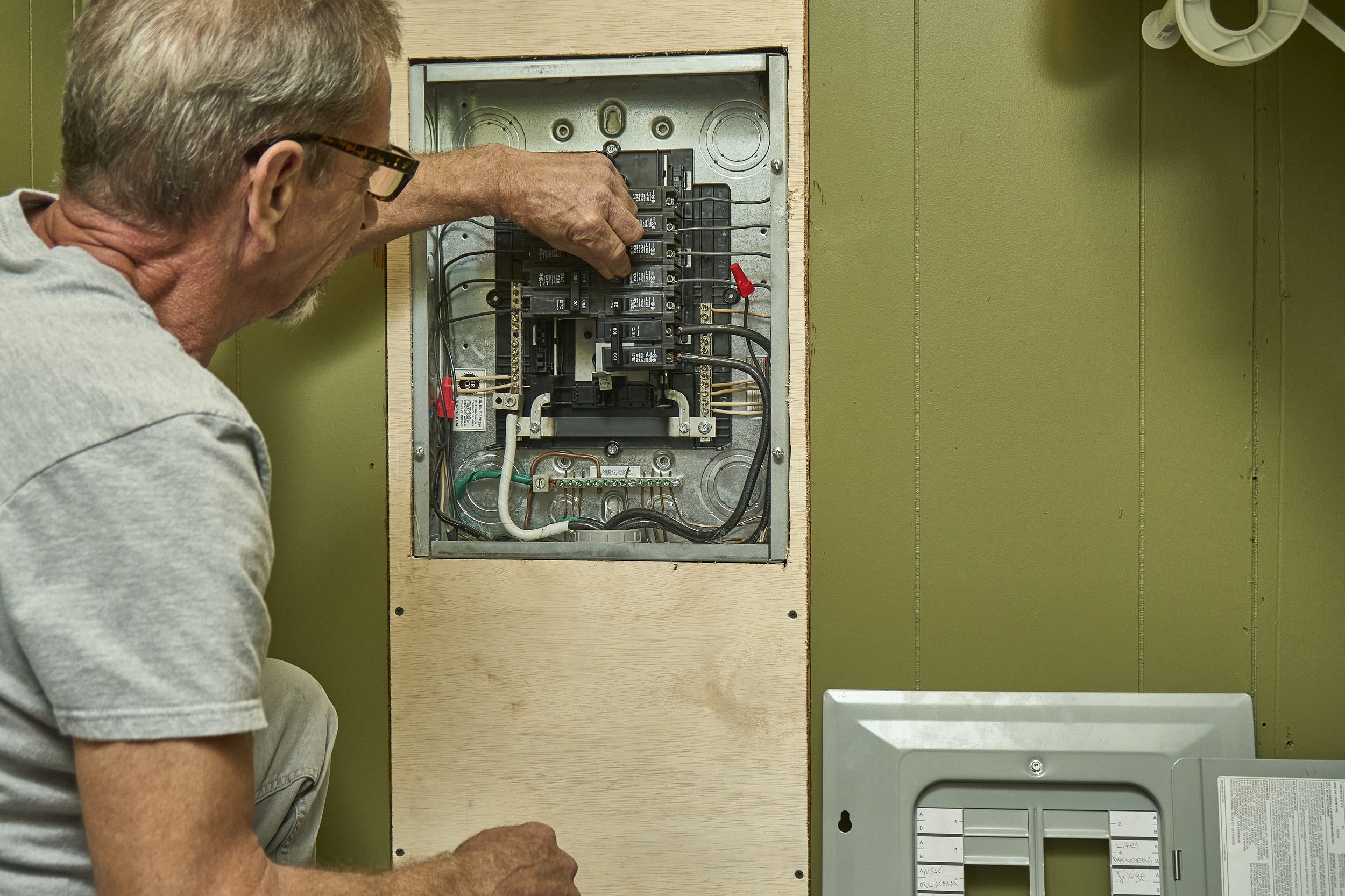 Kennedy Electric technician at an open residential electrical panel.