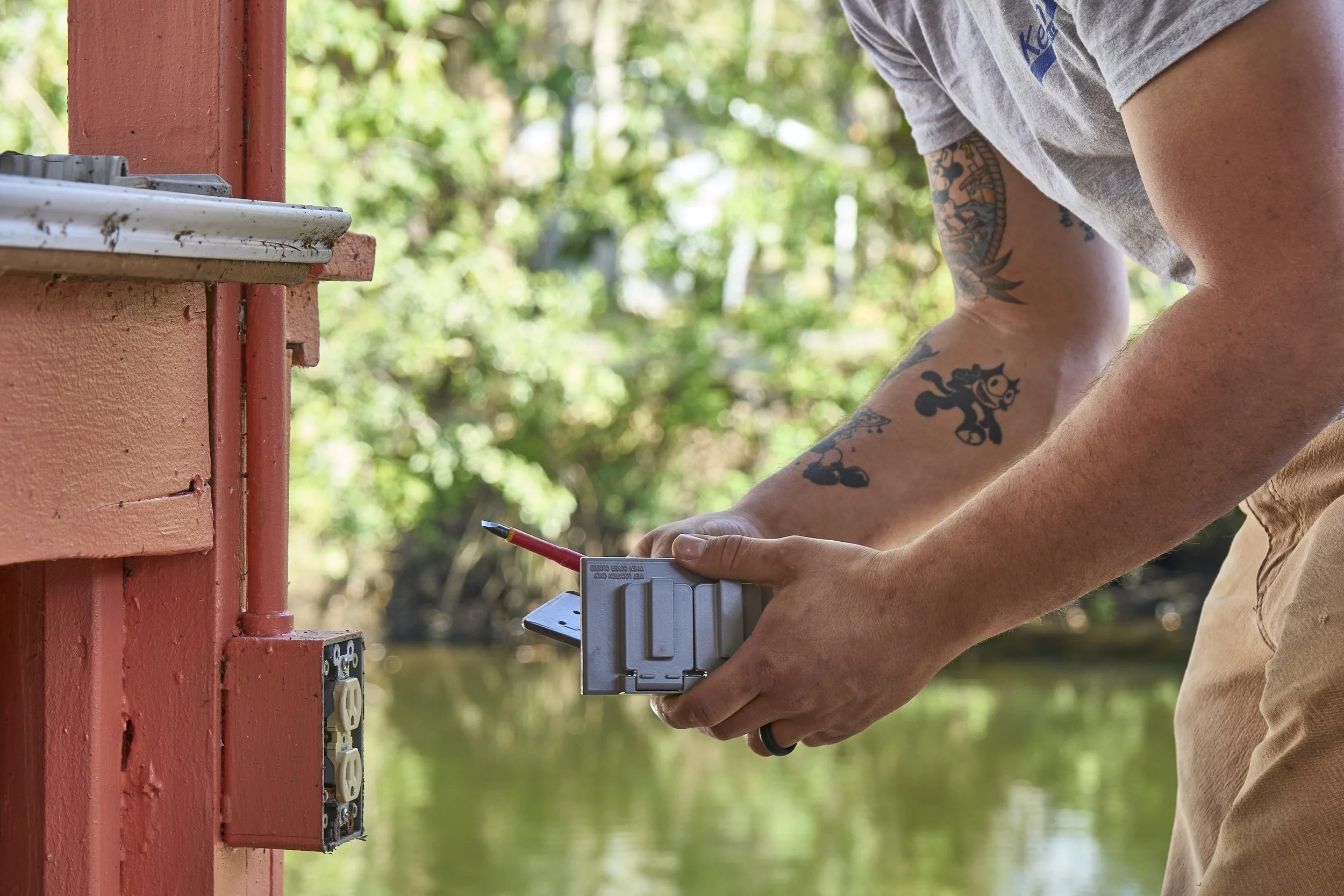 Man using a tool at an exterior dock post/box near water