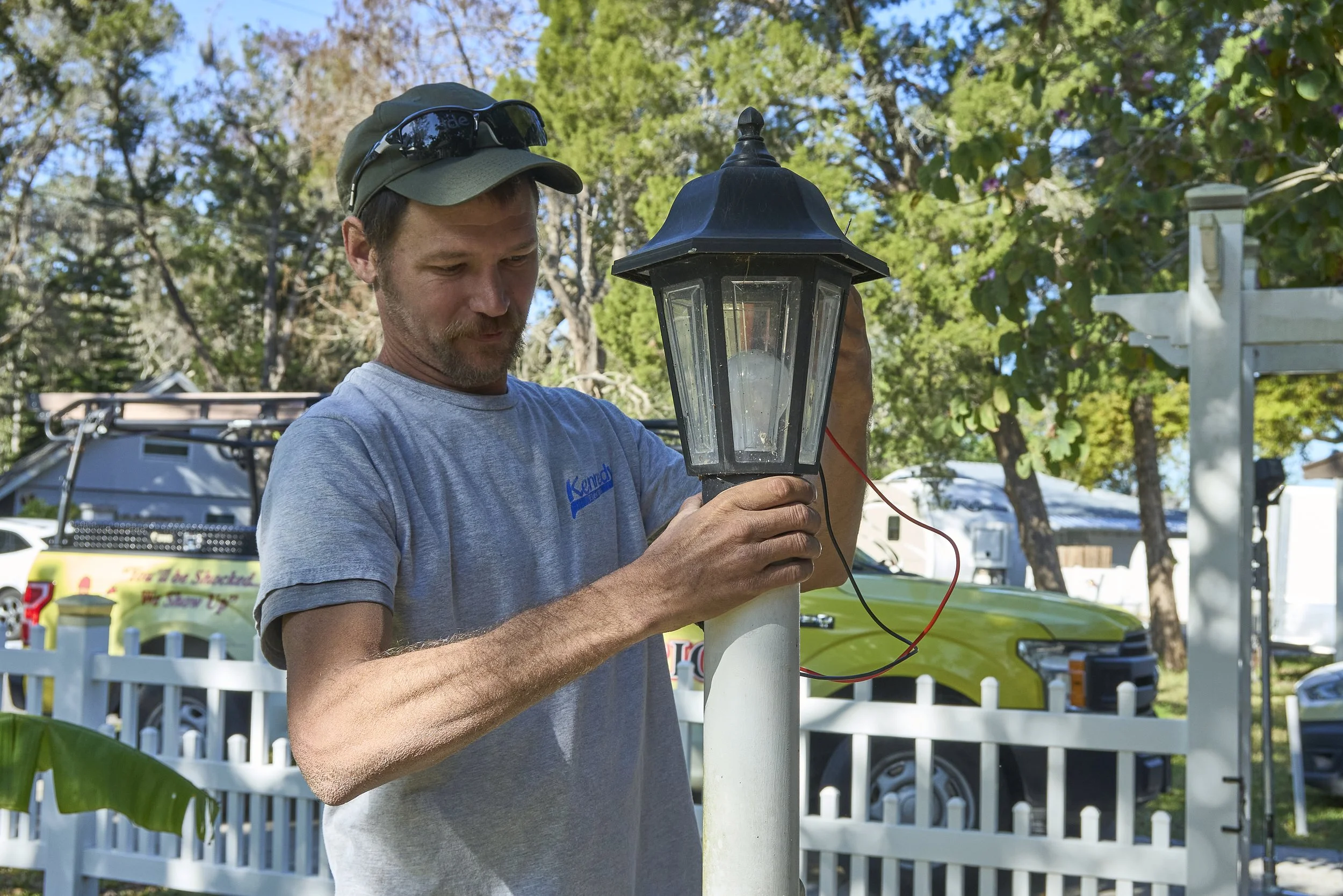 Man installing a coach lantern light on a white column
