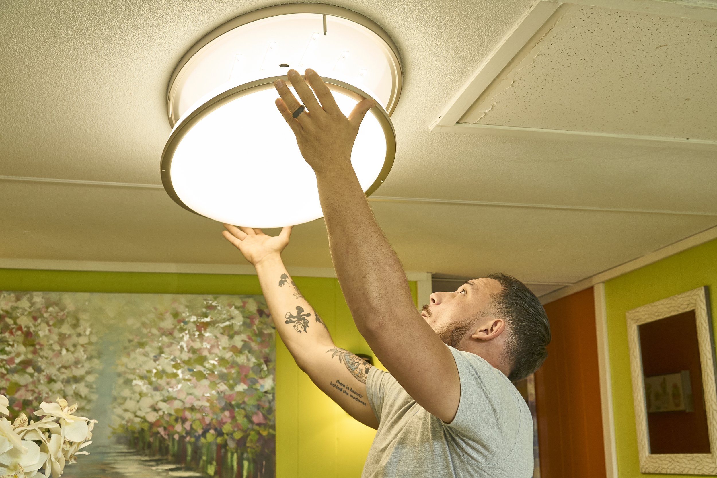 Man installing a round flush ceiling light indoors
