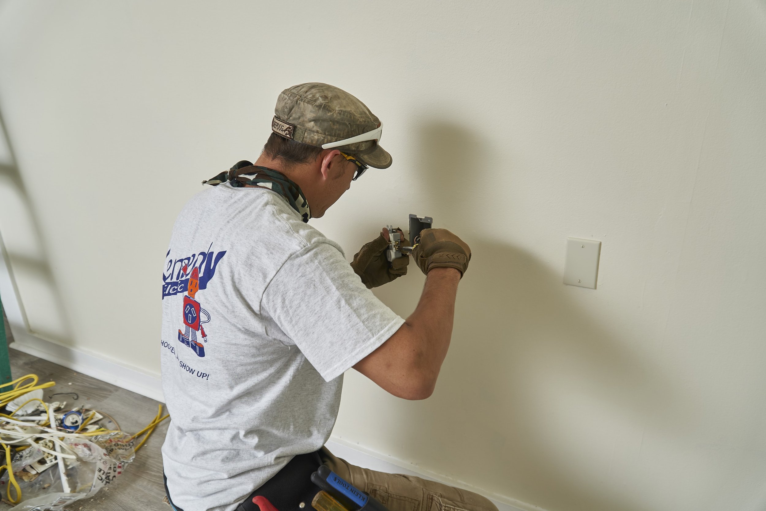 Electrician installing a wall box/outlet during rough-in wiring (Romex visible)