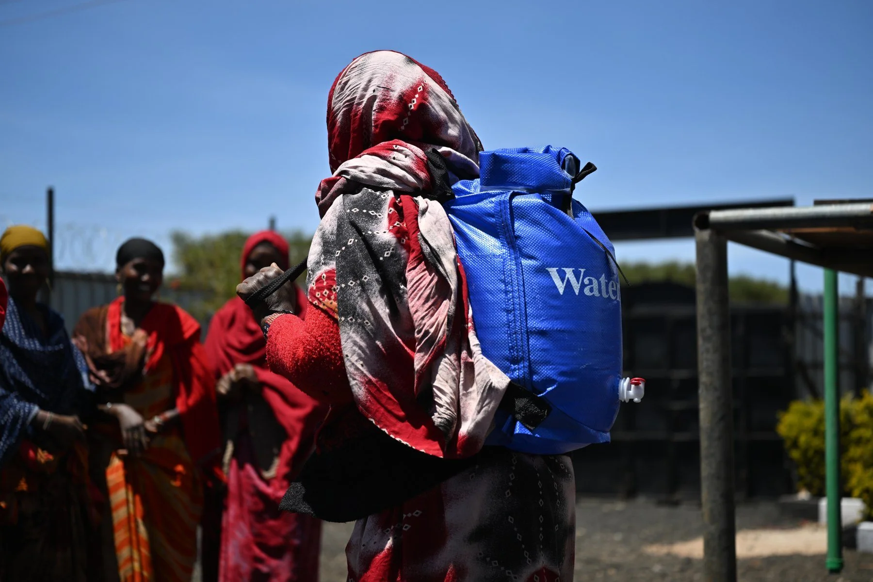 A woman wears a vivid blue WaterSafe Pack, with its sealed top, shoulder straps and dispensing tap clearly visible.