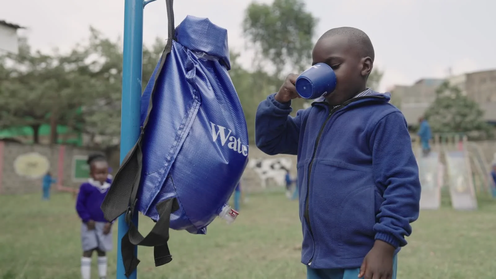 A student drinks from a blue cup beside a WaterSafe Pack.