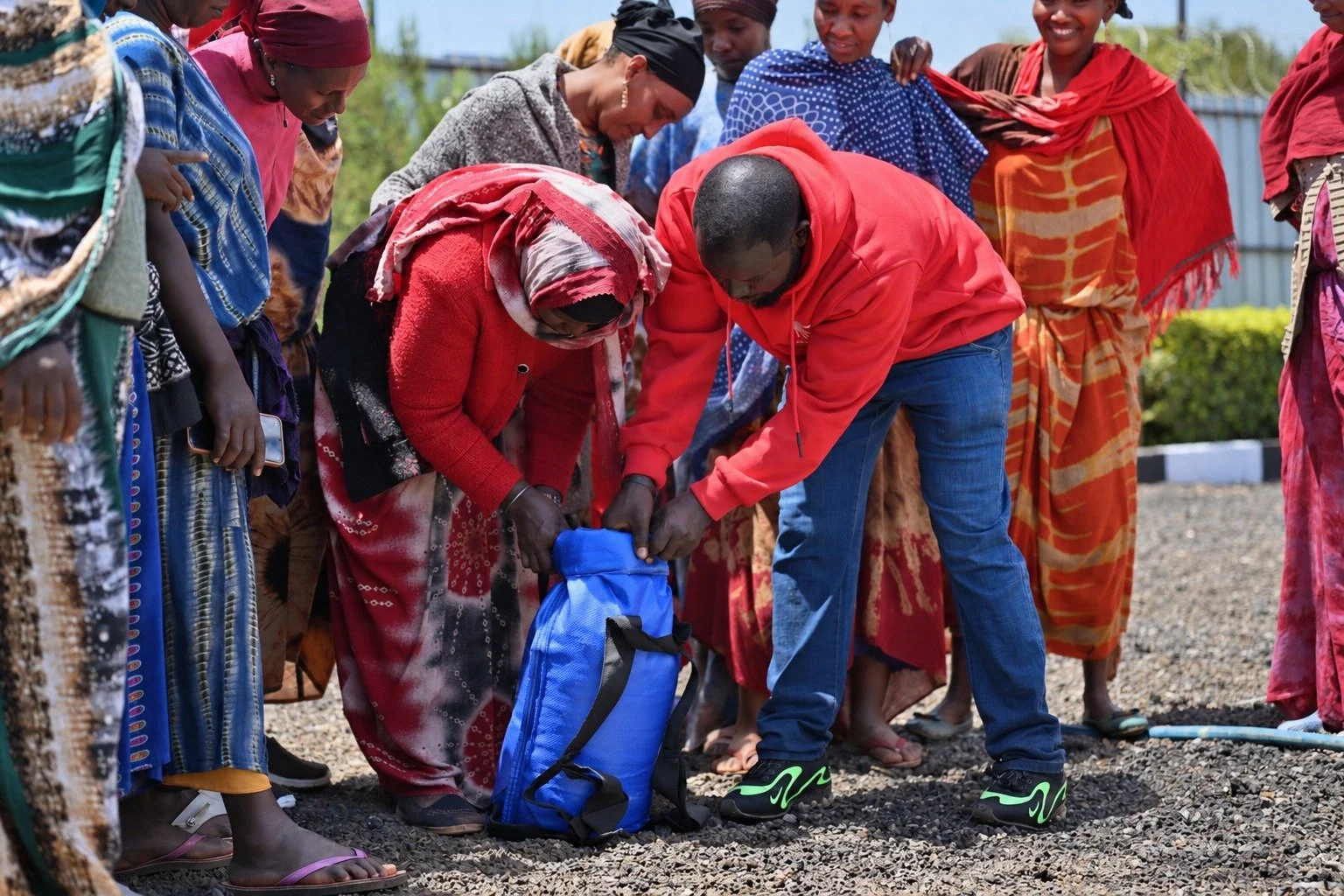 In bright daylight, a woman and a team member demonstrate the opening of a blue WaterSafe Pack together.