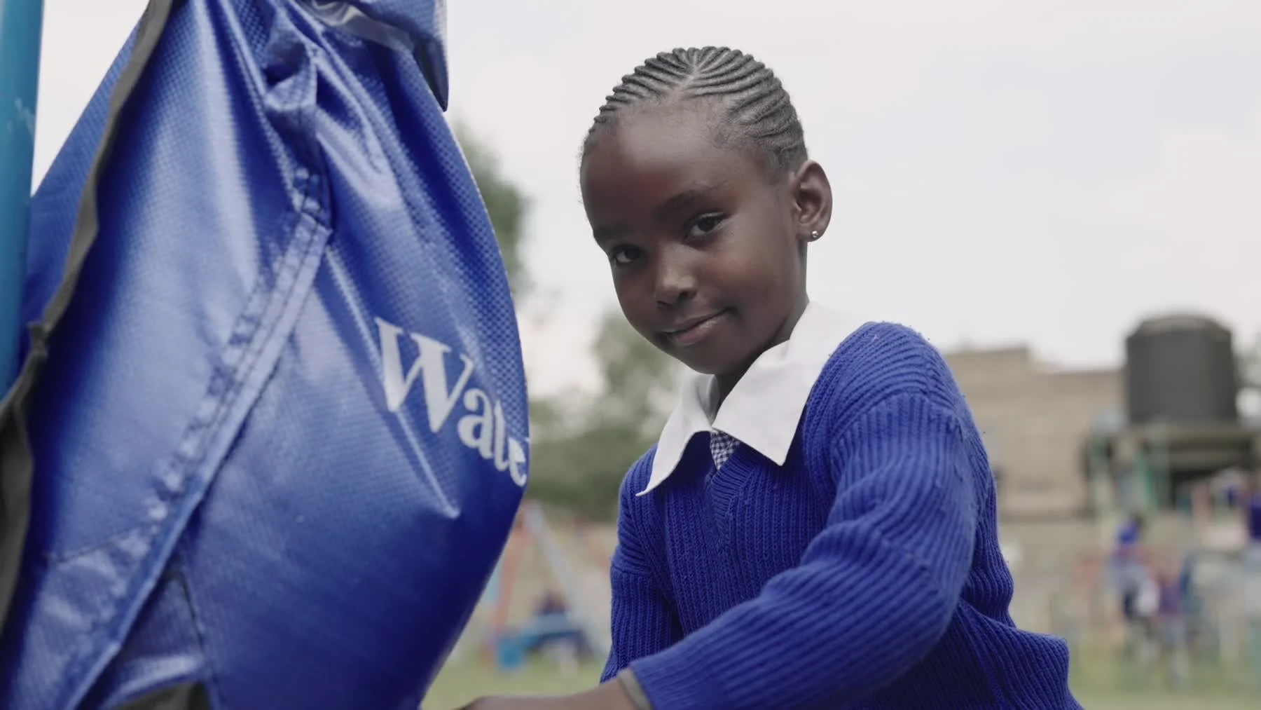 A smiling schoolgirl beside a blue WaterSafe Pack in the trailer’s final shot.