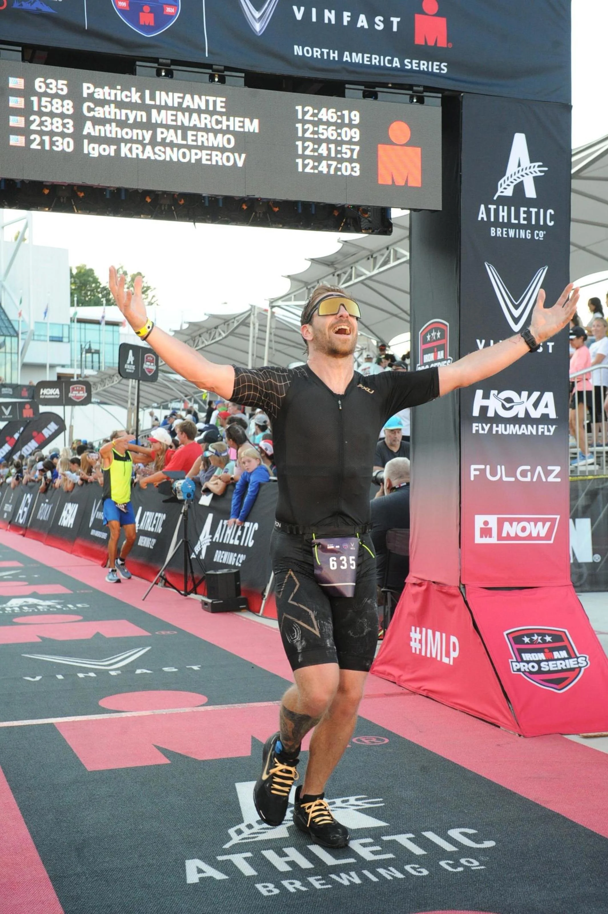 Patrick Linfante finishing Ironman Lake Placid in daylight in 2024 with 12:46:19 on the finish board