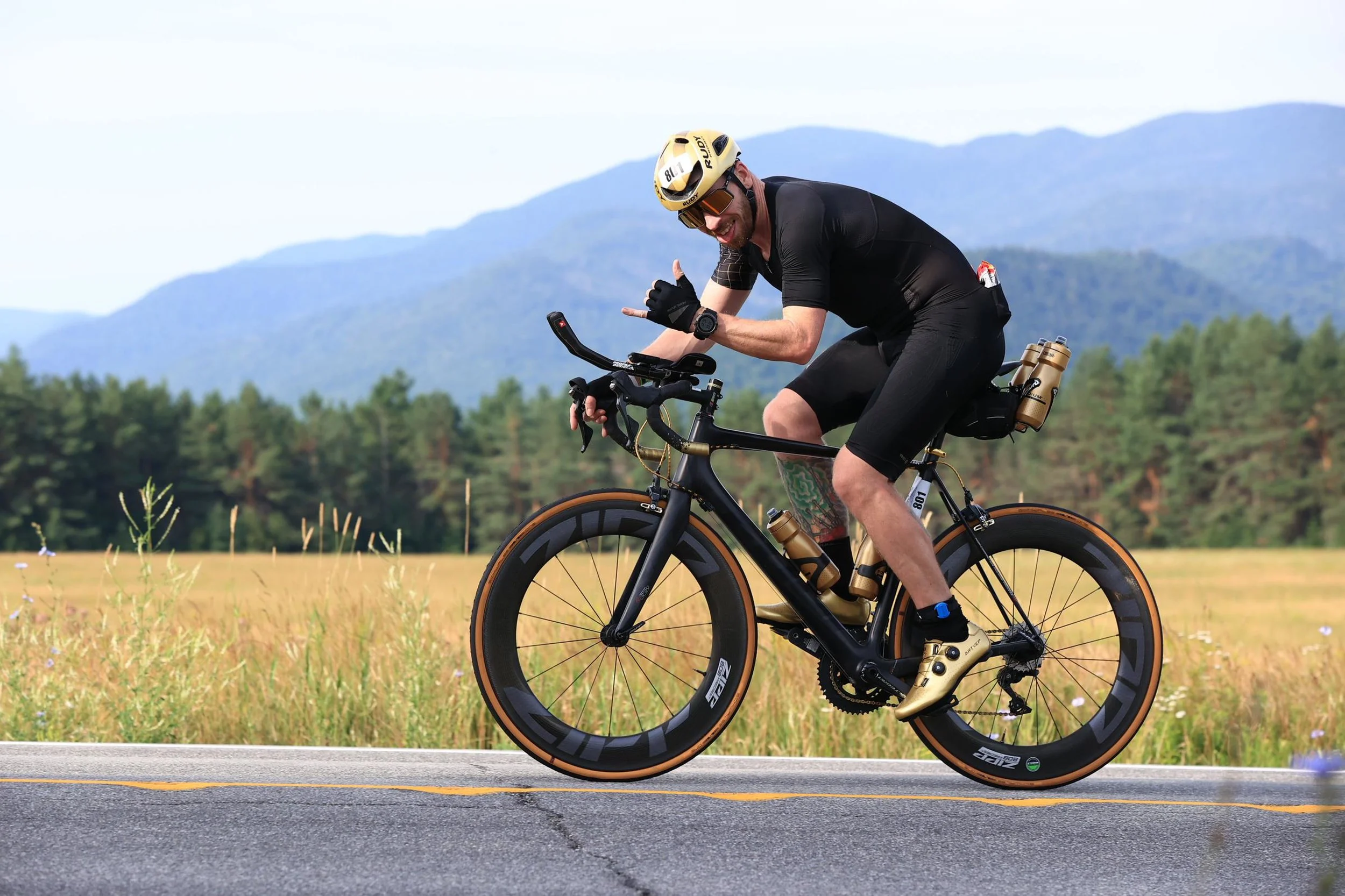 Patrick Linfante riding his gold accented bike with mountains behind him