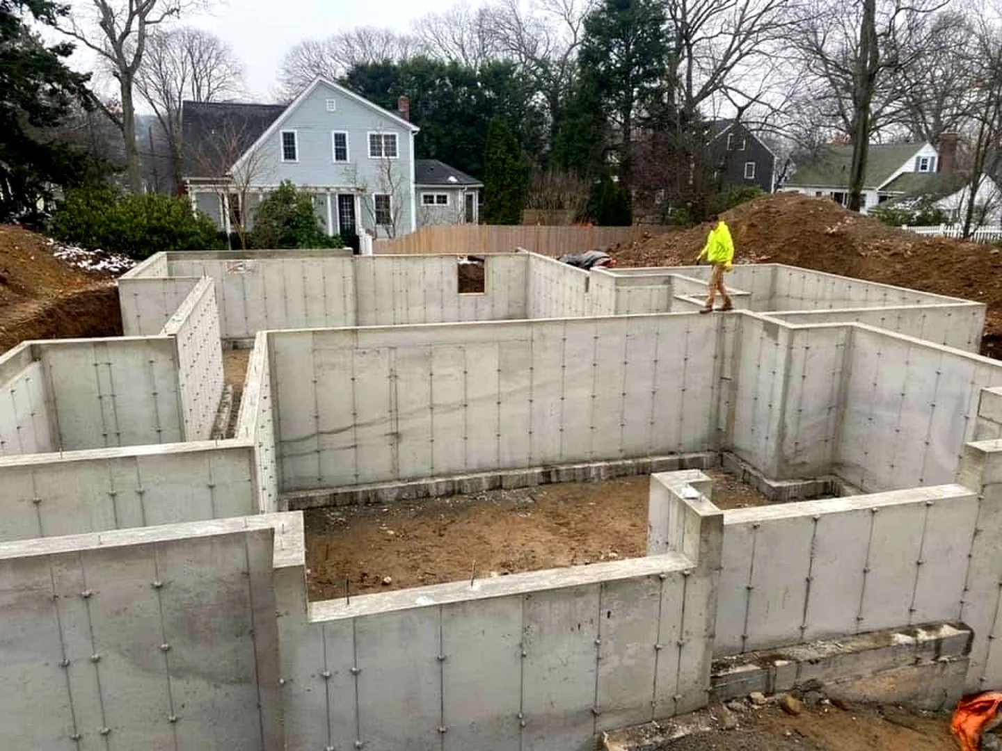 Concrete foundation walls with a white house behind the jobsite