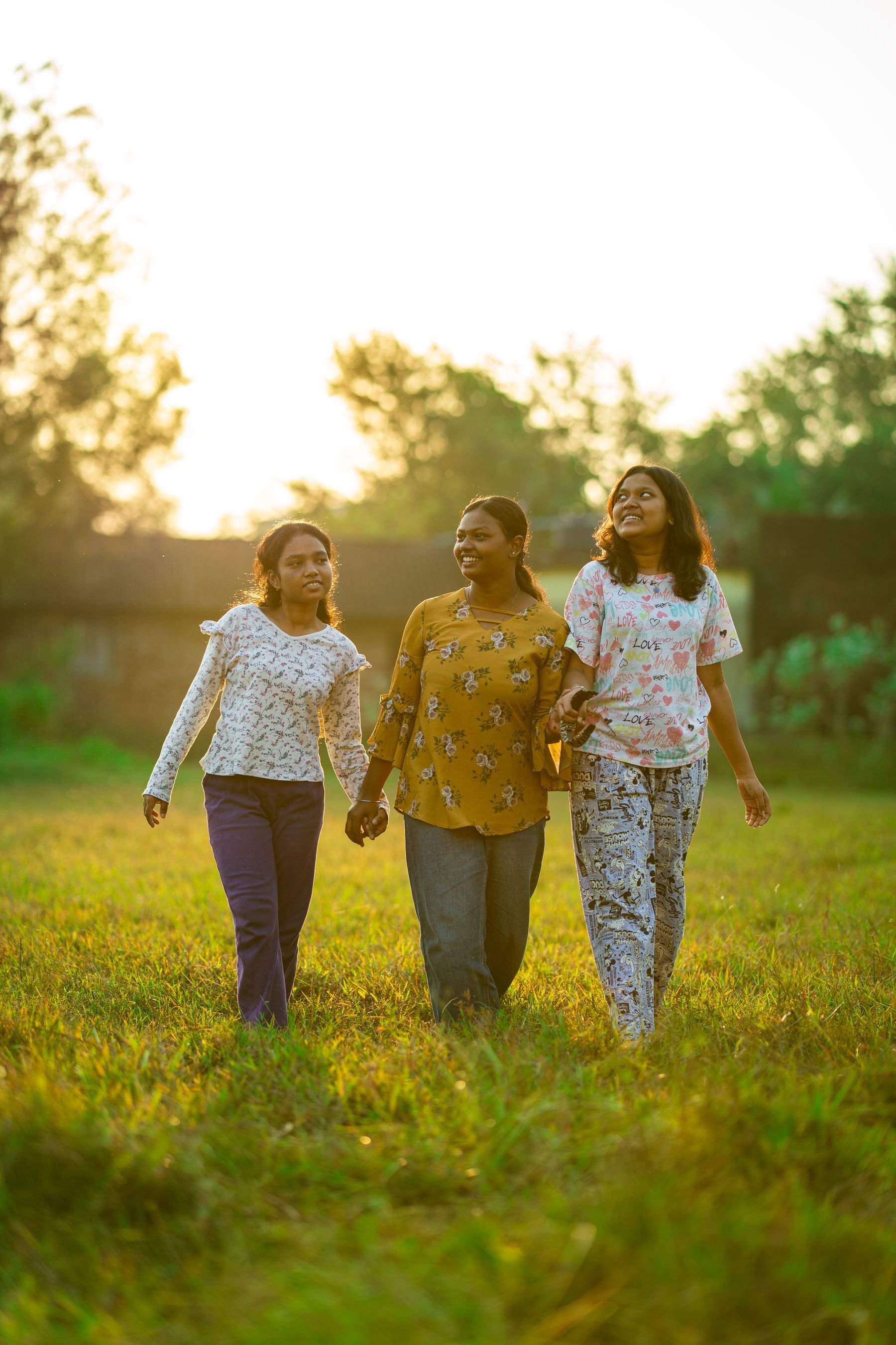 Three young women walking through a sunny field