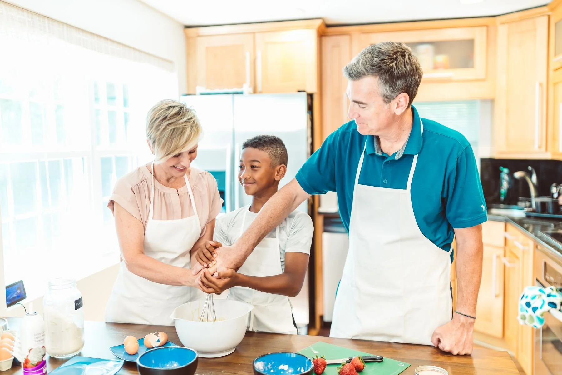 Parents and son cooking together in a bright kitchen