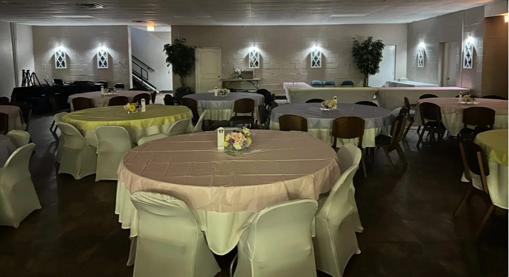 UTR Dinner Theatre dining room with round tables, covered chairs, and floral centerpieces