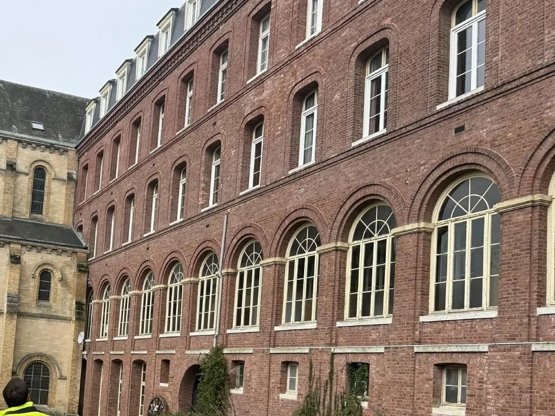 Façade d’un grand immeuble ancien en briques, avec ses hautes fenêtres