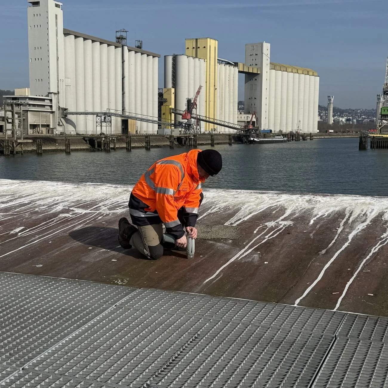 Diagnostiqueur NORDIAG en prélèvement sur un ponton portuaire, devant des silos