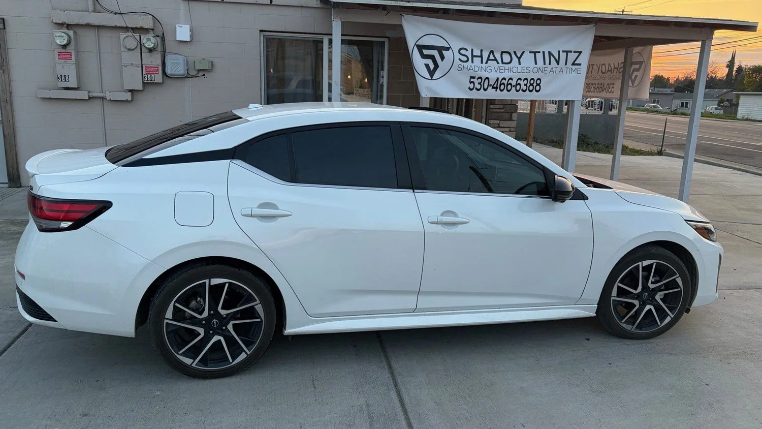 White Nissan Sentra with window tint at sunset outside the Shady Tintz shop, Yuba City