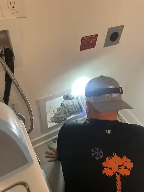 Latitude 32 technician cleaning a dryer vent with removed lint visible