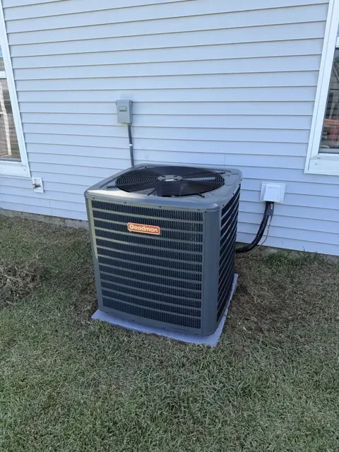 Goodman outdoor AC unit installed on an equipment pad beside a home