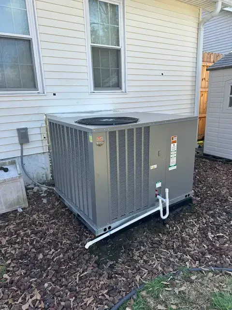 Ruud package HVAC system beside a home