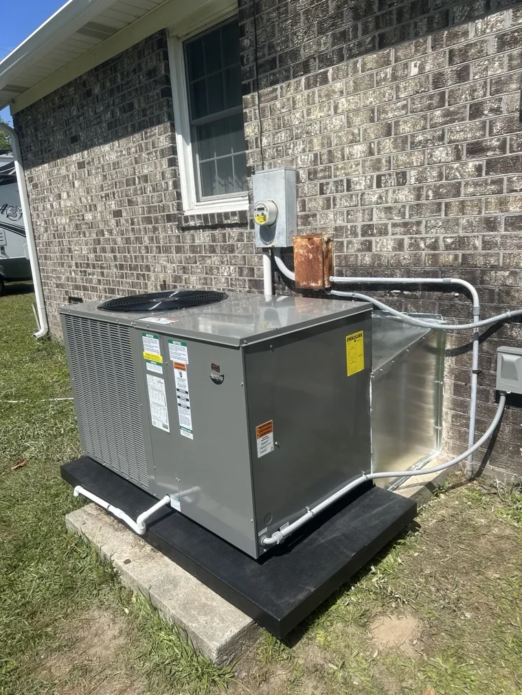 Outdoor HVAC unit on a pad beside brick siding