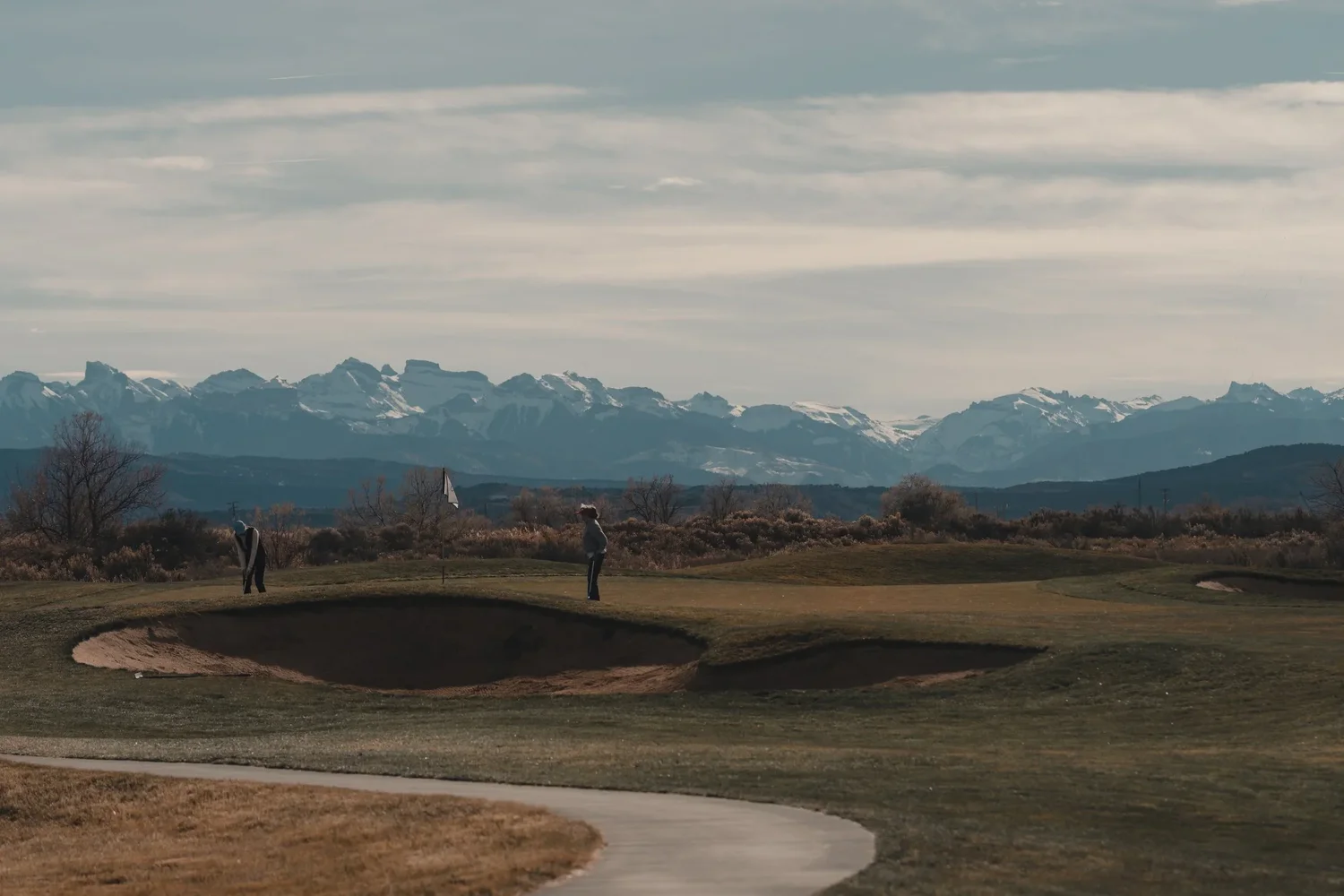 Winter fairways and a bunker beneath mountains on the Western Slope.
