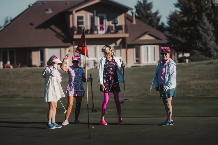 Players in pink gather on the green near the clubhouse.