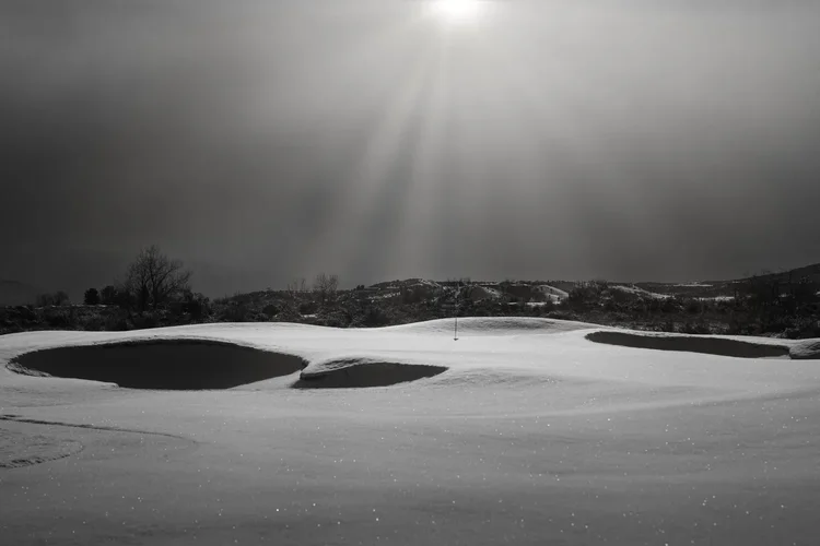 Sunlight over snow-covered bunkers, photographed in black and white.