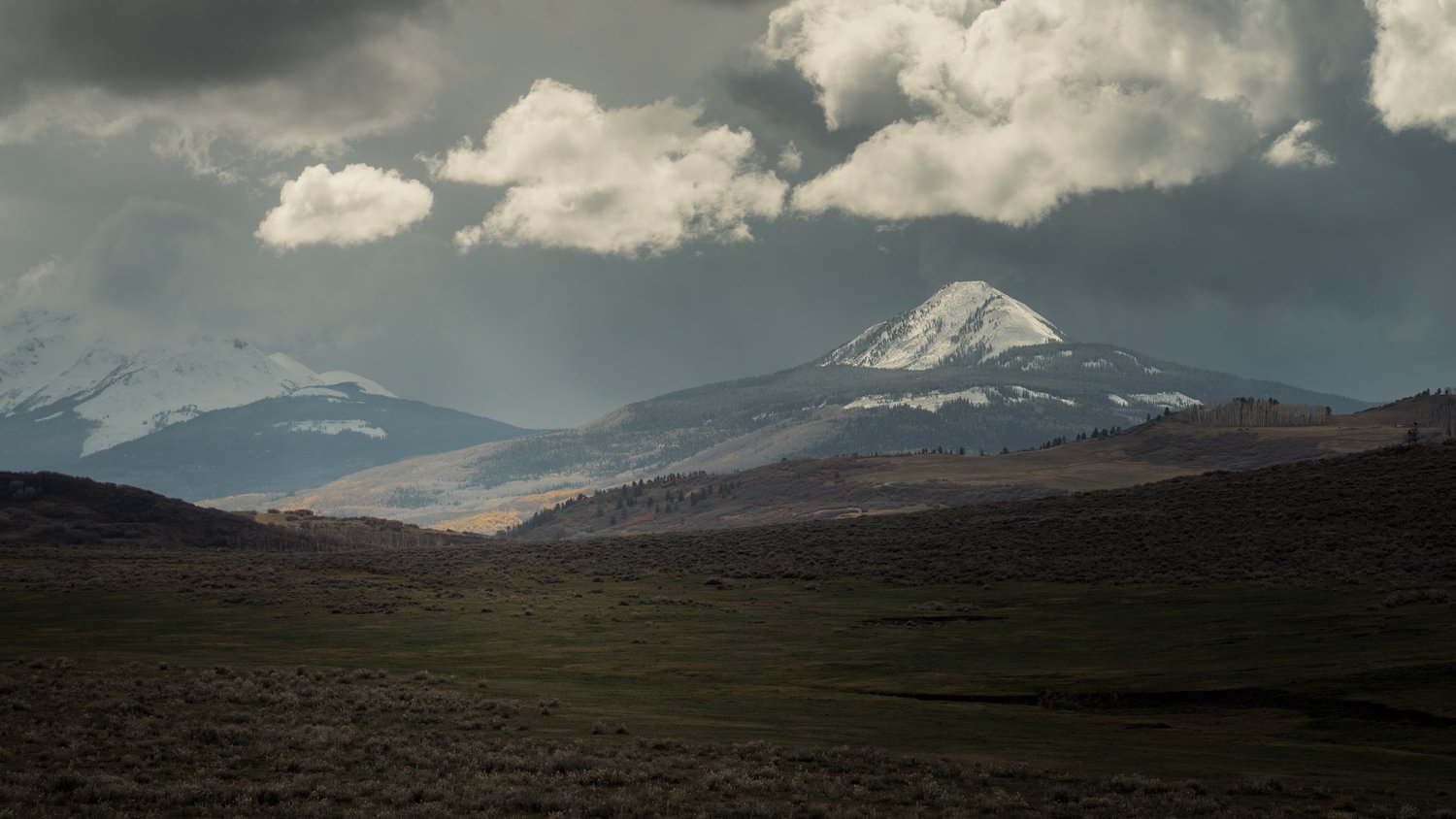 Snow-covered San Juan peaks above open sagebrush country near Telluride.