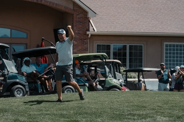 A player finishes a swing as other golfers watch.