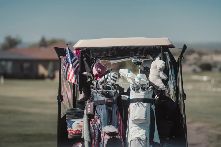 Golf bags and clubs on a cart decorated for the tournament.