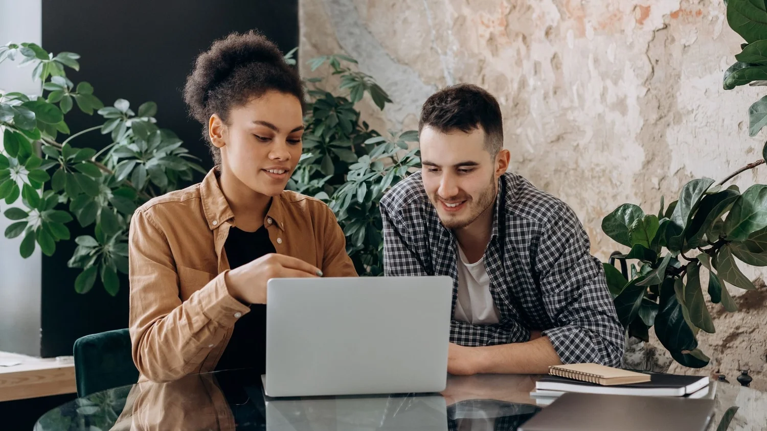 Two people working through something together on a laptop
