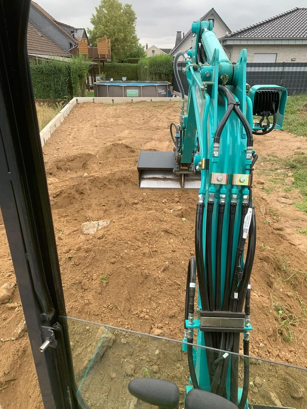 Minibagger beim Aushub auf einem Baugrundstück, Blick aus der Kabine