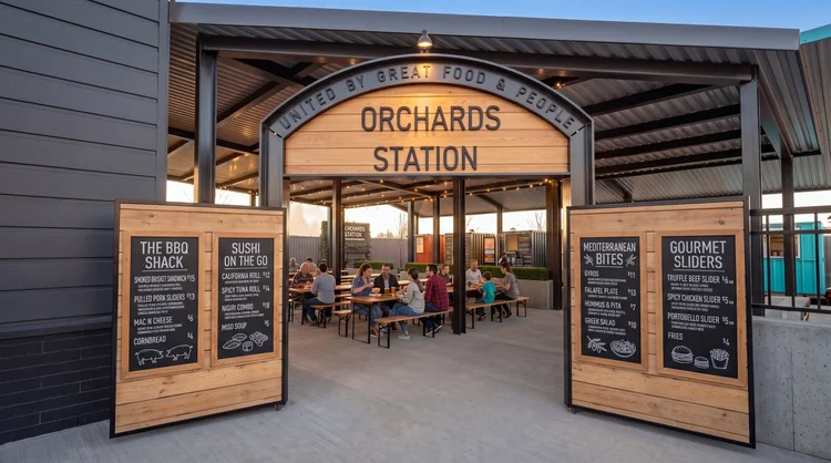 Orchards Station entry arch with menu boards and guests dining under the covered pavilion