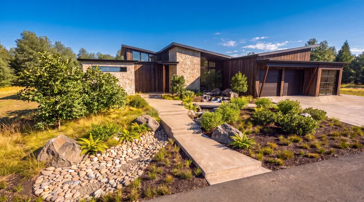 Vancouver Residence front in daylight, with stone and dark wood siding and a landscaped walkway