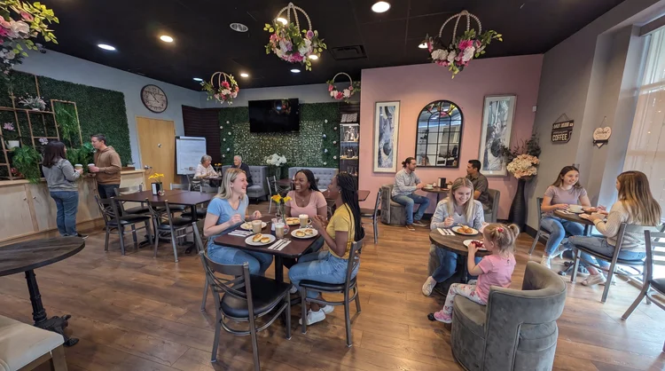Love & Appetite café seating with pink walls, a living green wall and hanging floral birdcages