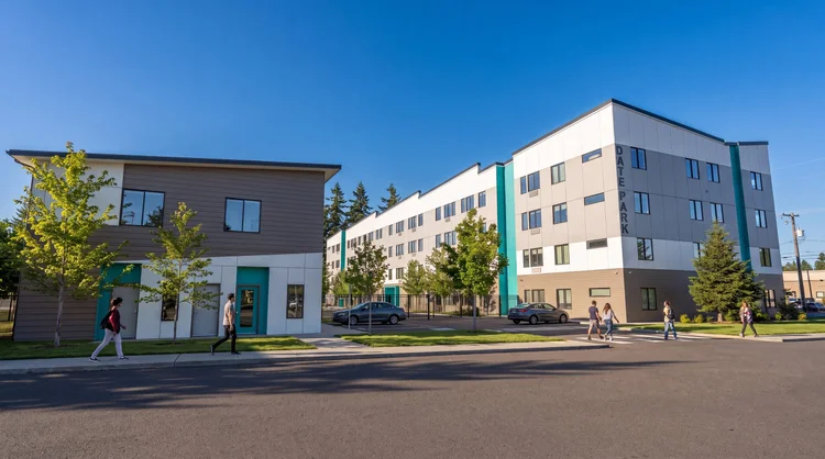 Date Park apartments from the street in daylight, with the DATE PARK sign and residents walking by