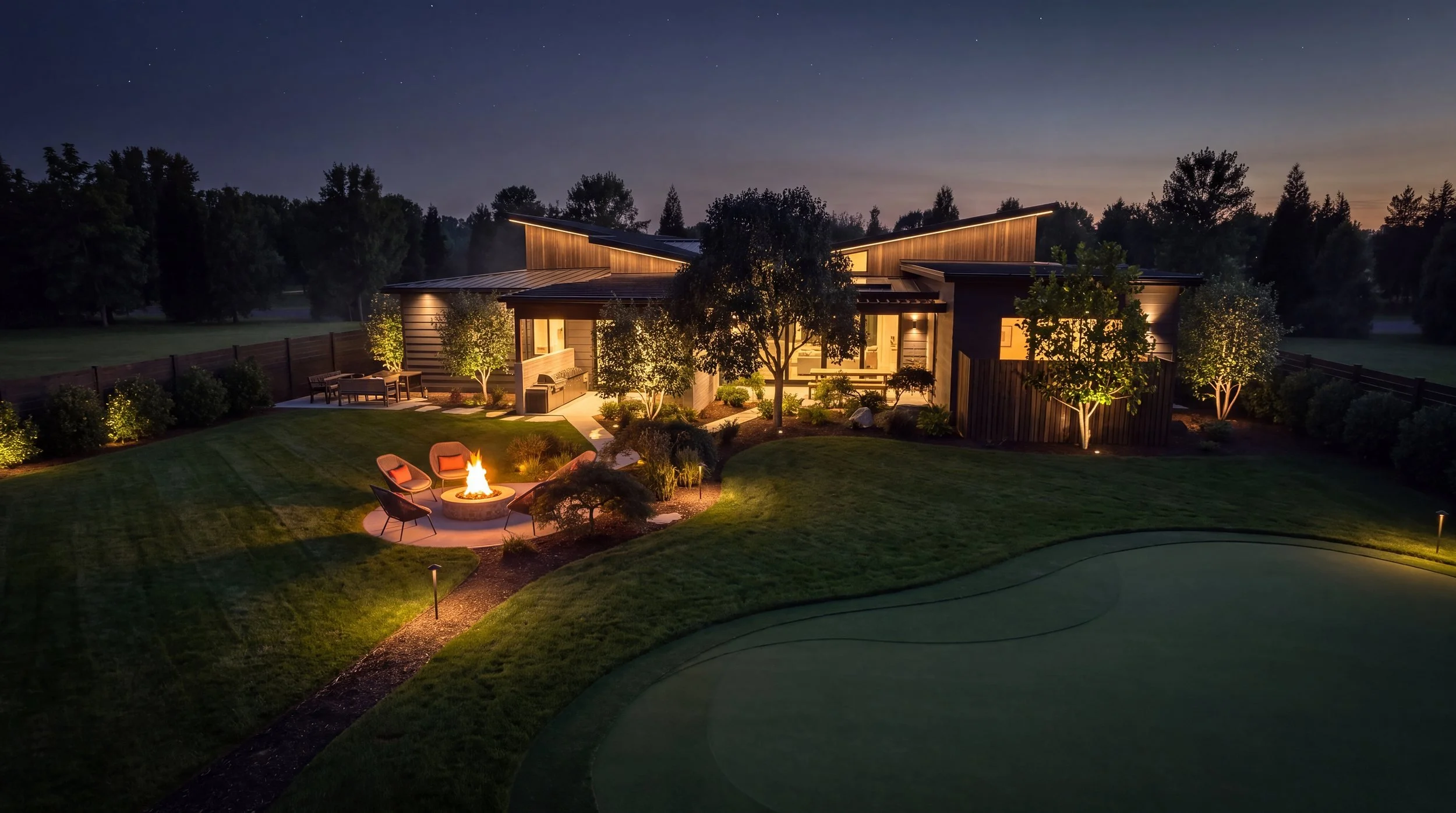 Vancouver Residence backyard at night with a lit fire pit and putting green