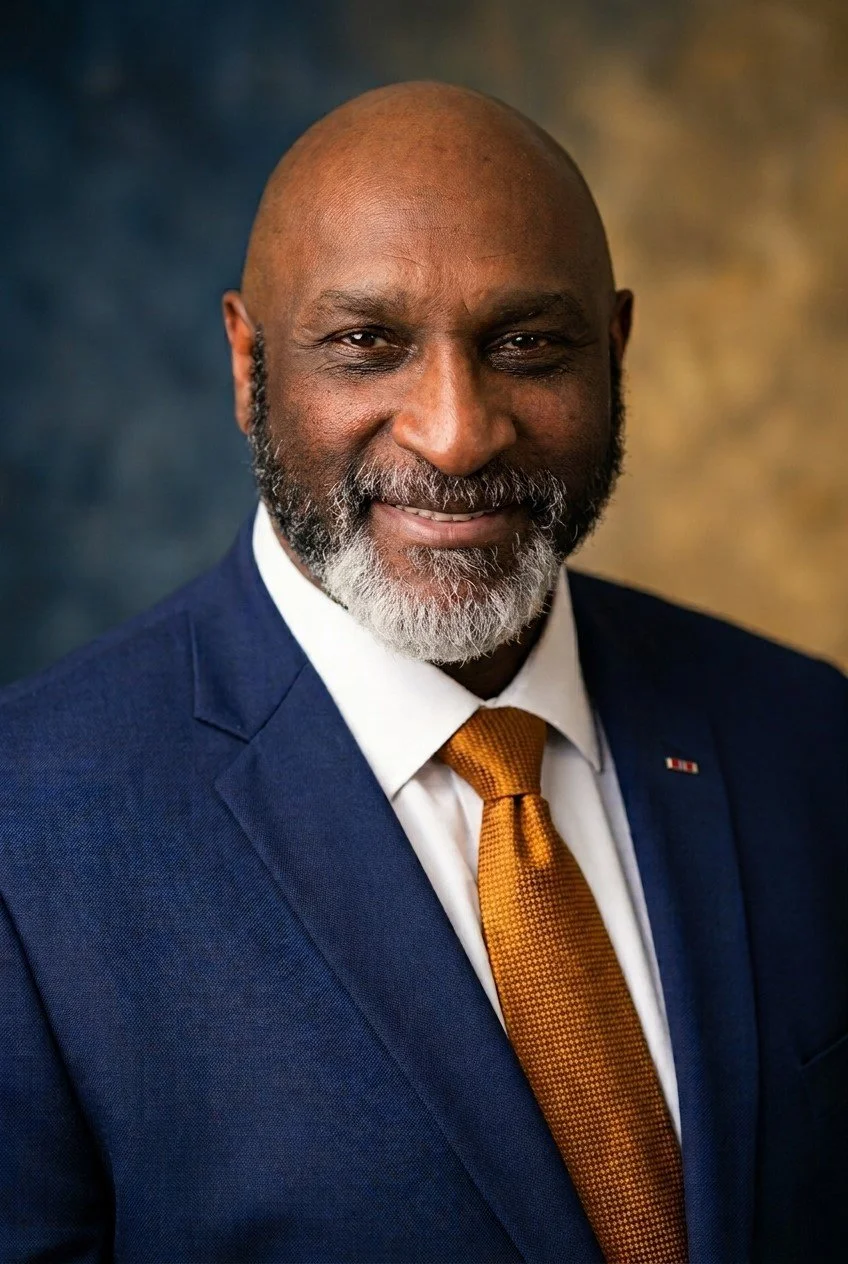 Portrait of Andraé Evans in a navy suit and gold tie