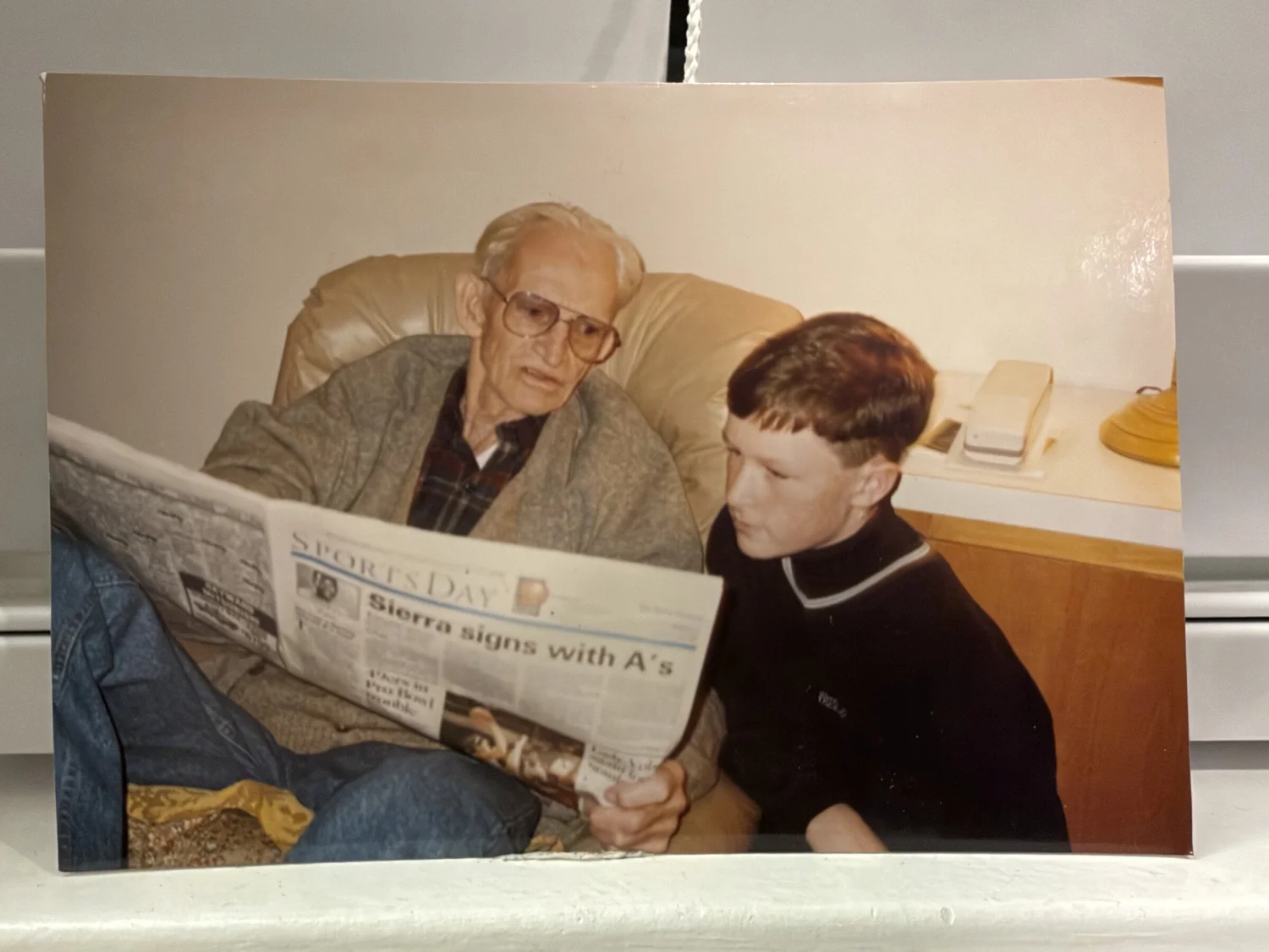 Grandpa Jack reading the sports page with Mike as a boy, headline Sierra signs with A's